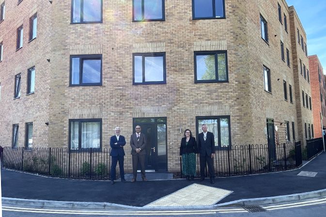 four people stood in front of modern apartment block.