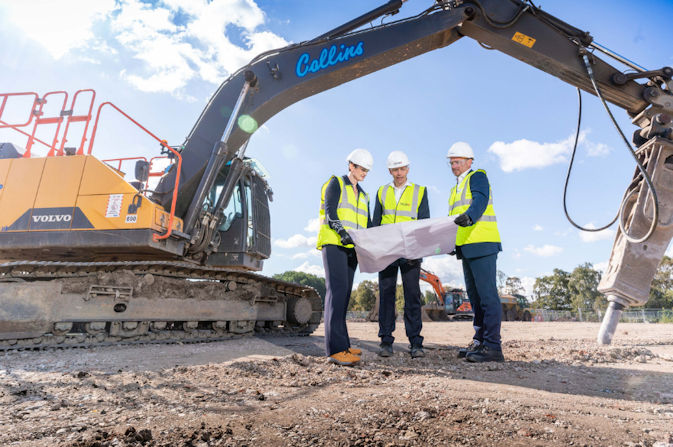 Jackie Wild, Andrew Pilsworth and Paul Simpson looking at a document next to construction equipment