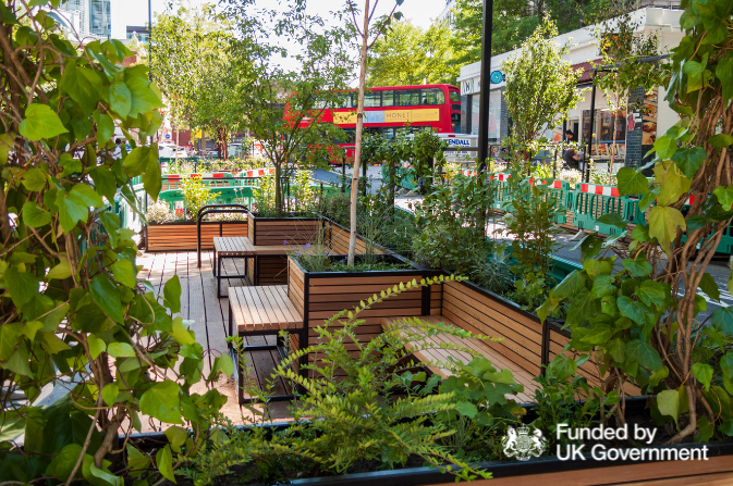 A parklet pocket park situated next to a road, surrounded by plants and trees