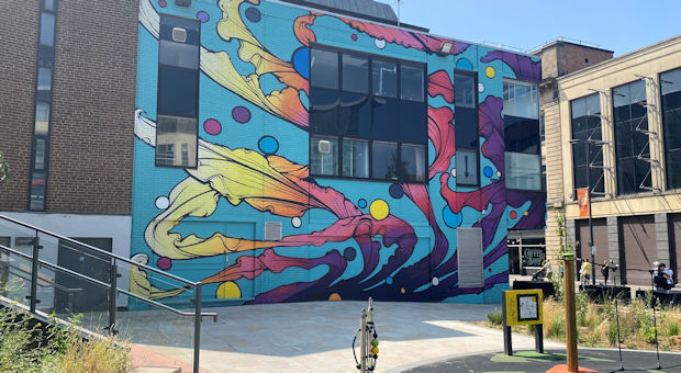 Brightly coloured mural on the side of a building on East Street. A new play area has been built in front of it.