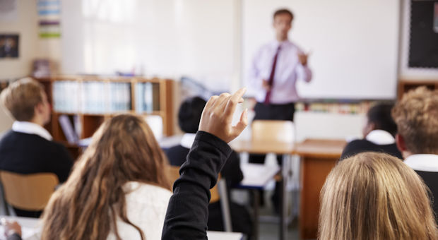 Student holding their hand up in a classroom