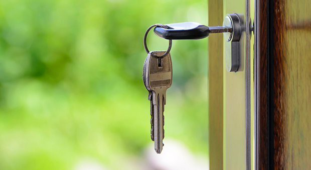 Keys hanging from a front door lock. The door is wide open