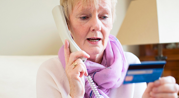 Senior woman on landline giving her bank details to a caller