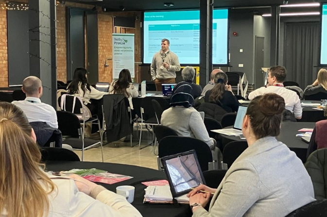 A group of teachers sitting at tables listening to a presentation