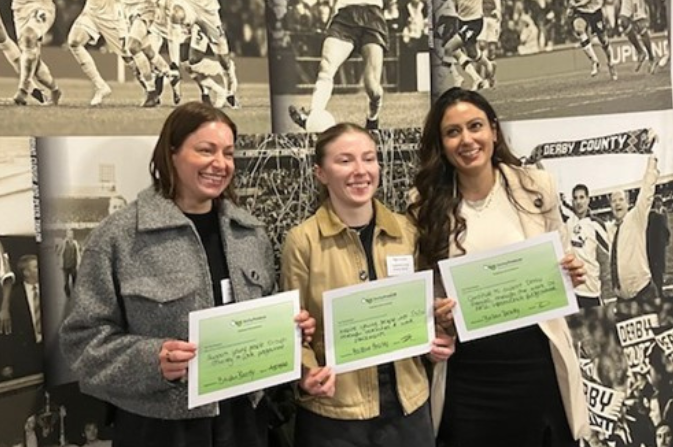 Three smiling young women holding up certificates