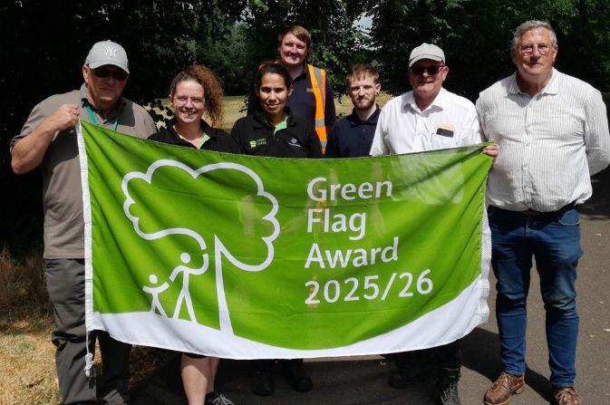 Members of the Derby Parks team holding up a banner to recognise the Green Flag Award accreditation 2025