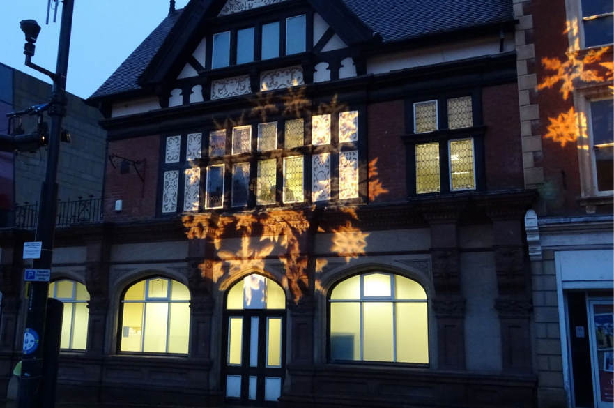 Lights in shape of snowflakes projected onto side of building