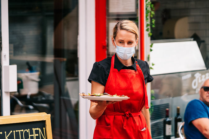 Waitress wearing a face covering while serving customers