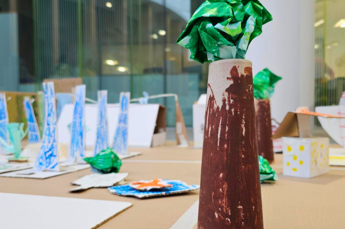 A tree made of painted cardboard in the foreground with other items made by children in the background. created as part of the Festival of Ideas about Climate Action