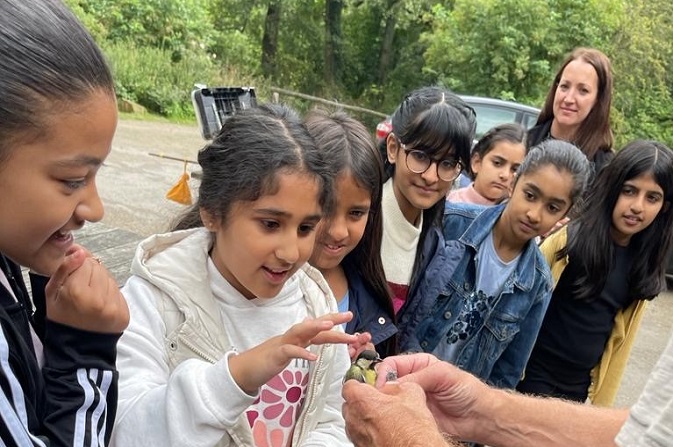 Children taking part in a Summer Holiday and Food Programme club stroke a bird at Hardwick Hall