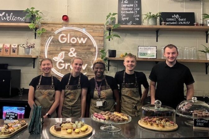 five smiling young people stand behind canapes they've prepared in a cafe