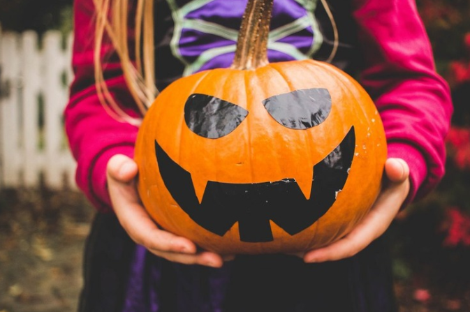 A young girl holding a decorated pumpkin