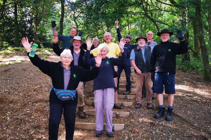 A group of parks volunteers smile and wave for the camera