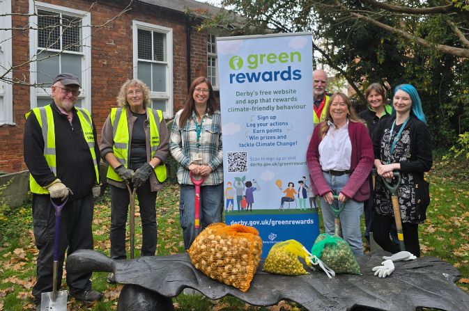 People standing either side of a banner saying 'Green Rewards'