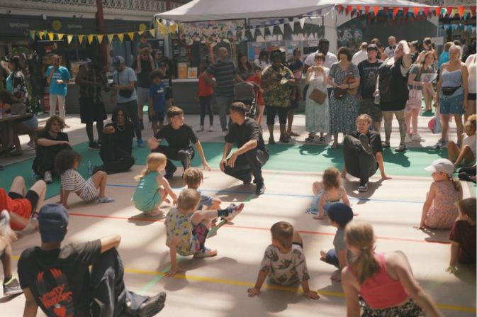 A group of children taking part in a creative activity inside a sunny Derby Market Hall