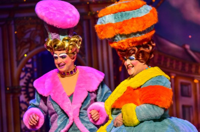The ugly sisters on stage in brightly coloured costumes during Cinderella