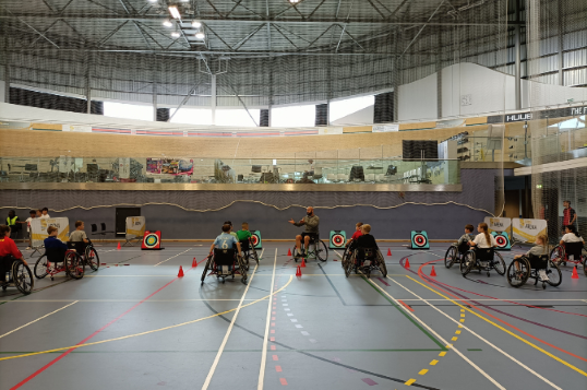 A wide shot of children taking part in a wheelchair archery session at Derby Arena