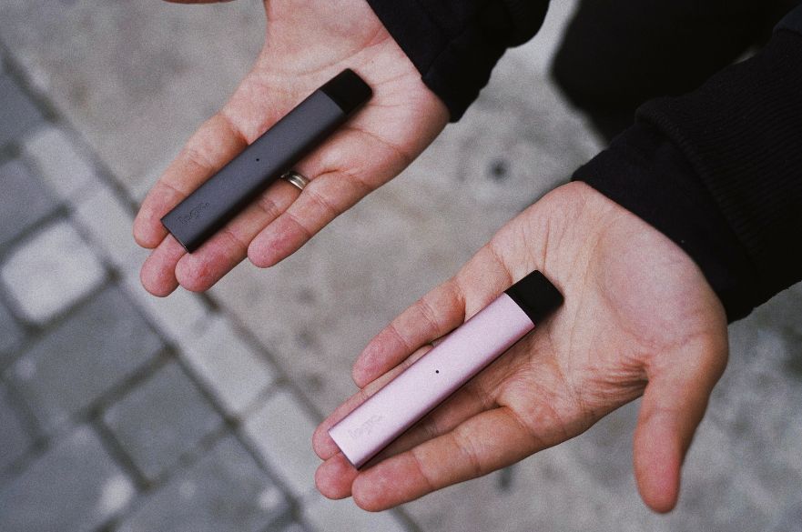 Two disposable vapes on two hands