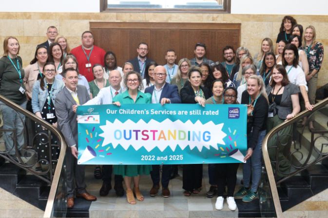 Children's Services colleagues holding up a banner celebrating their second Outstanding Ofsted rating