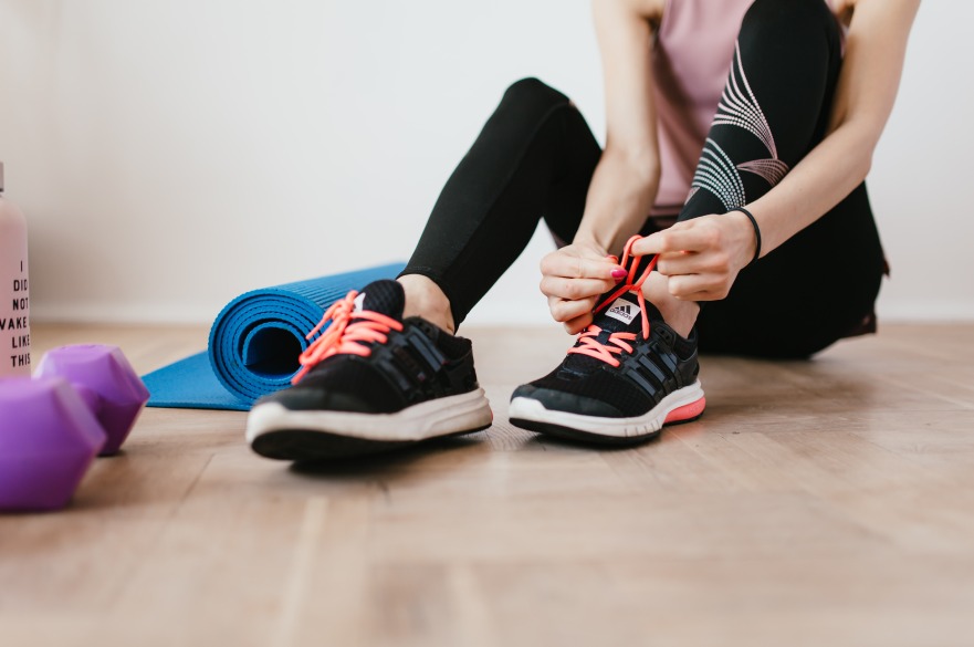 woman tying trainers with exercise equipment