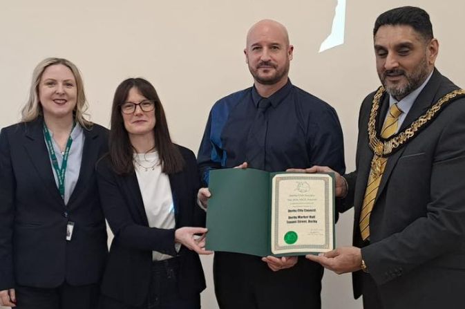 Three people accepting an award from the mayor