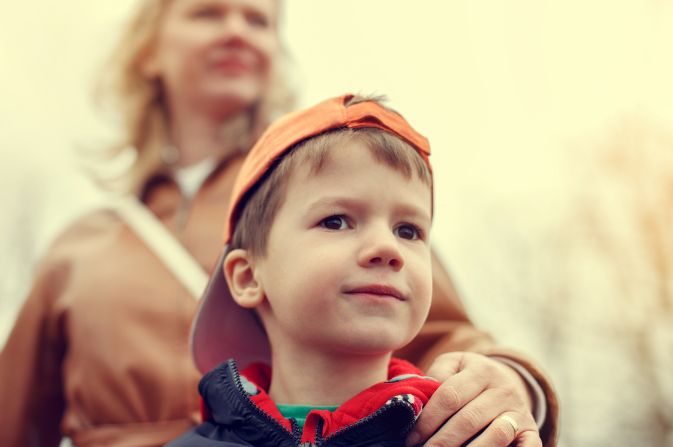 Women placing her hand on the shoulder of a boy in a hat