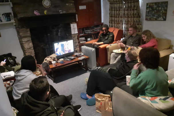 A group of young people enjoy watching TV together in their holiday accommodation