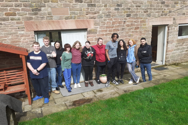 A group of young people outside their holiday accommodation in the Peak District