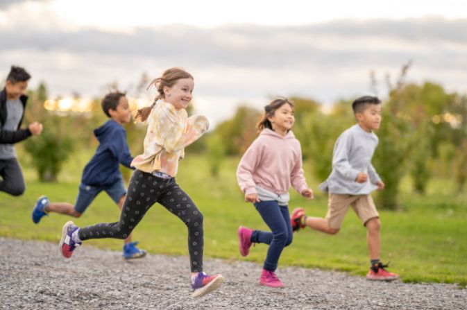 A group of children running through a park area