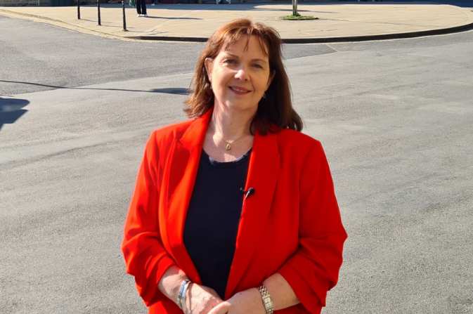 Middle aged white woman with brown hair in a red jacket