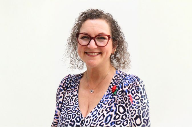 Headshot of a woman in a white and blue spotted dress.