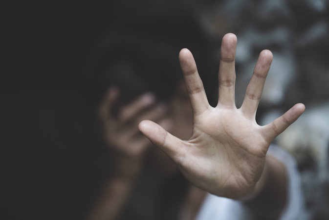 Person holding their hand up to shield themselves