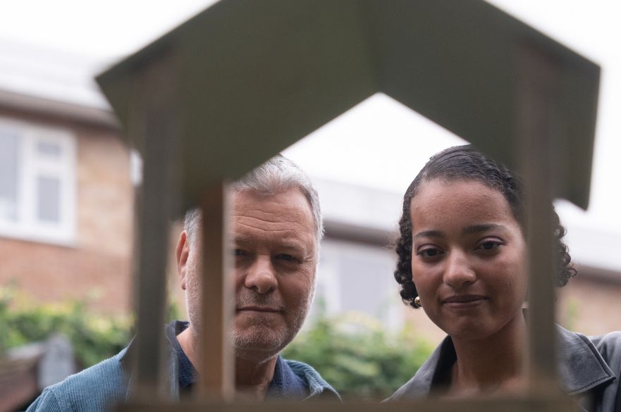 Carer and young woman looking at a bird feeder.