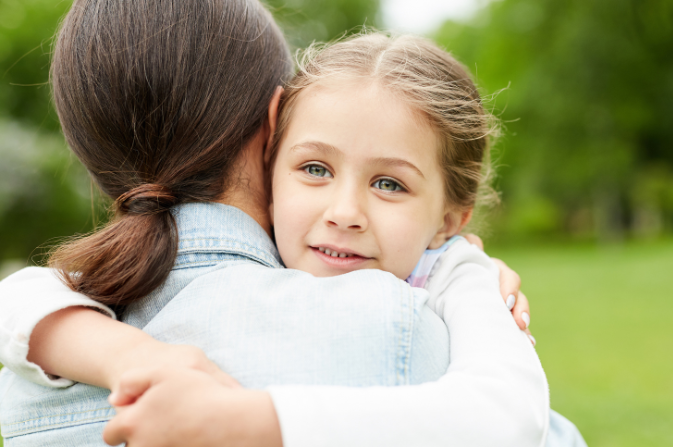 A young child hugs her mother