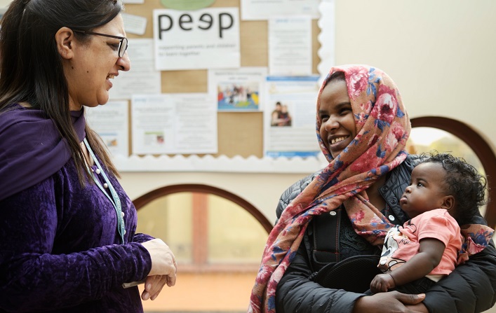 Family Hub staff member chats to a mum who is holding a young child