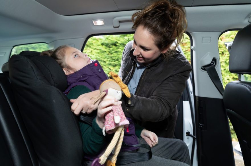 Parent helping disabled child with car seat