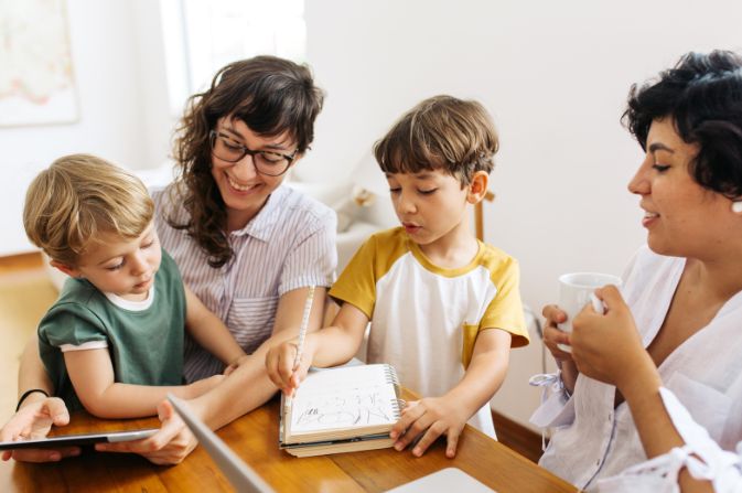 Two females and two boys at a table drawing