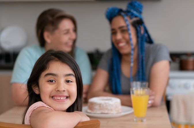 Two females at a table with a child smiling