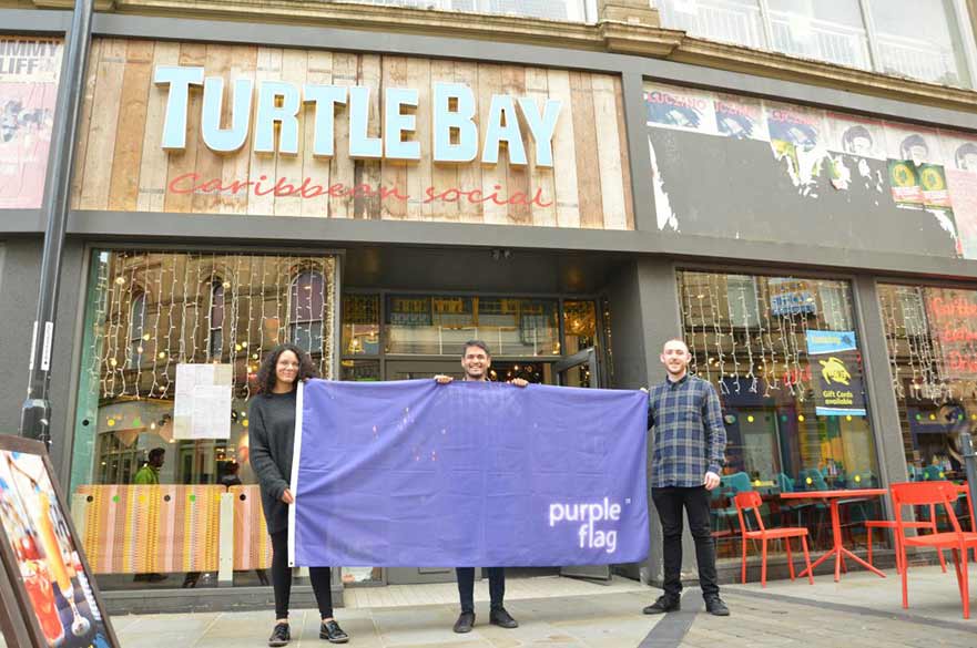 People holding flag outside Turtle Bay restaurant