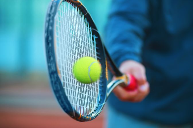 close up view of a person hitting a tennis ball with their racket