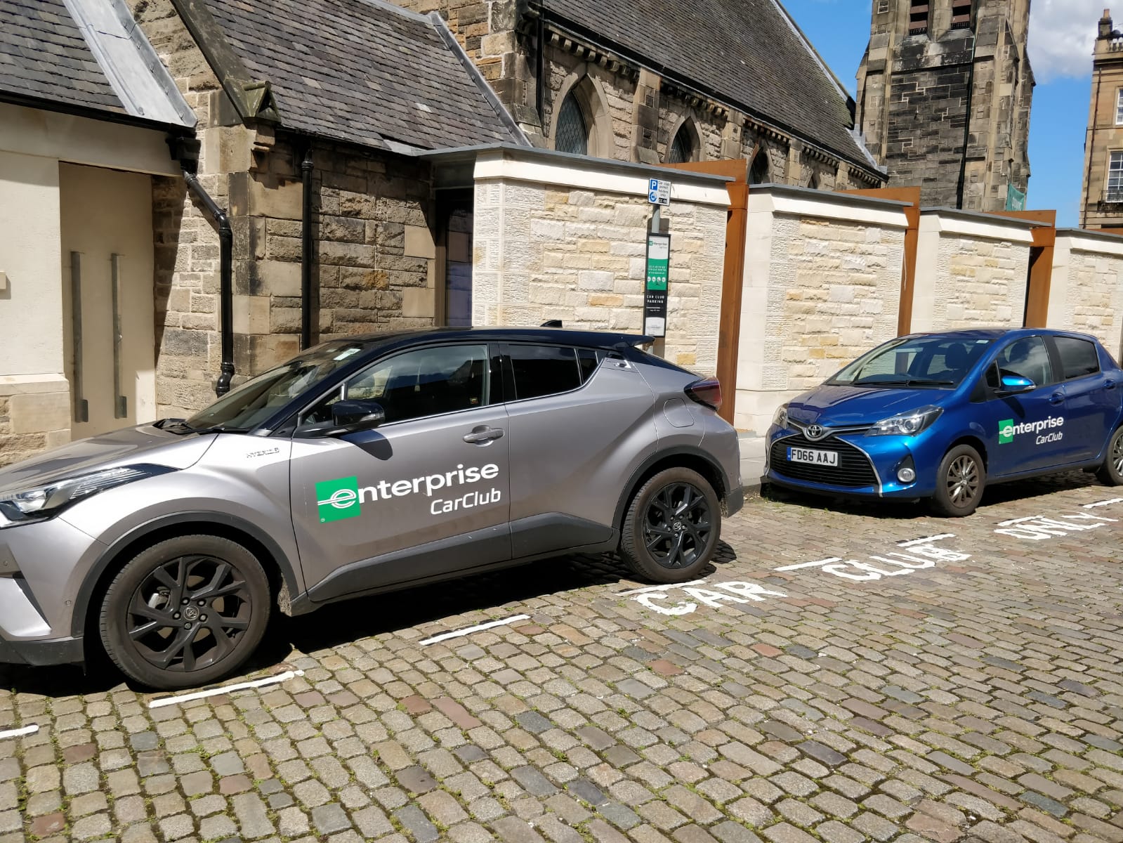 Two Enterprise Car club cars, one blue and one grey, parked in a car club bay.