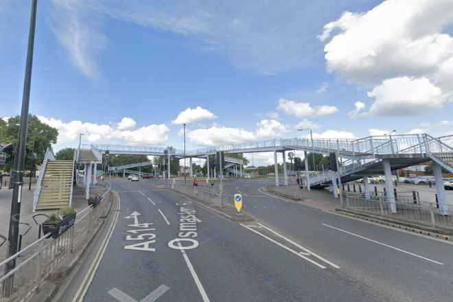 Road leading to major junction with traffic lights and pedestrian bridges.