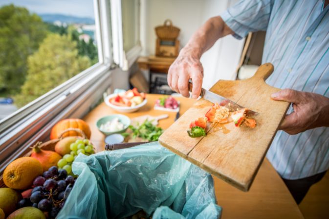 Food waste on a board being scraped into a caddy