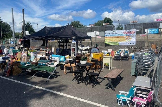 The image shows the exterior of a Reuse pop-up shop event, with multiple items on display.